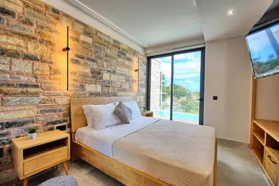 a bedroom with a brick wall and a bed and a window at Villa Kallos by PosarelliVillas in Païdhokhórion