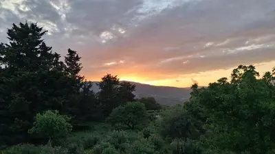 a sunset over a forest of trees with the sun setting at Stone villa Halepa panoramic view, private pool,big garden & quiet in Néon Khoríon