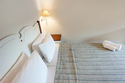 a hotel room with a bed with white sheets and pillows at Frideriki Studios & Apartments in Plataniás
