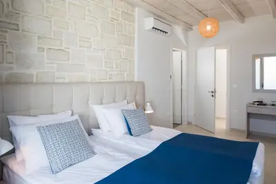 a bedroom with a white bed and a stone wall at Falasarna Luxury Villas I Private 