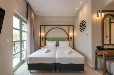 a bedroom with a large bed with white sheets at El Greco Hotel in Chania Town