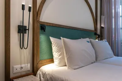 a bed with a wooden headboard and white pillows at El Greco Hotel in Chania Town