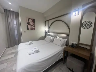 a bedroom with a large white bed and a table at El Greco Hotel in Chania Town