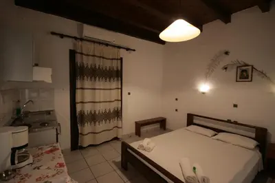 a bedroom with a large bed and a kitchen at Chania Rooms in Chania Town