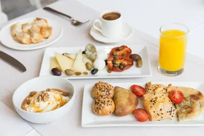 a table with plates of food and a glass of orange juice at Kydon The Heart City Hotel in Chania Town