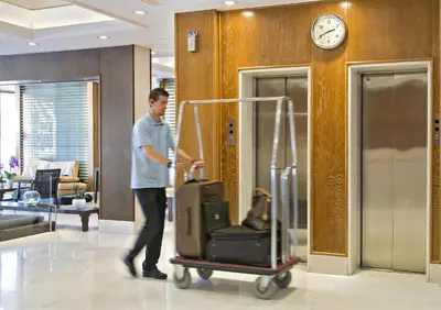 a man walking through a lobby with a cart of luggage at Kydon The Heart City Hotel in Chania Town