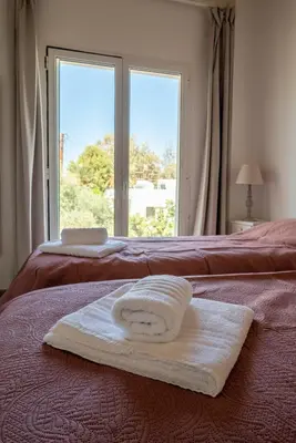 a towel sitting on a bed with a window at Villa Meltemi in Daratso