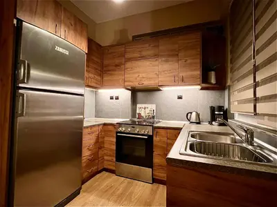 a kitchen with wooden cabinets and a stainless steel refrigerator at Odyseia Apts I at the center of the City & Old Town in Chania Town