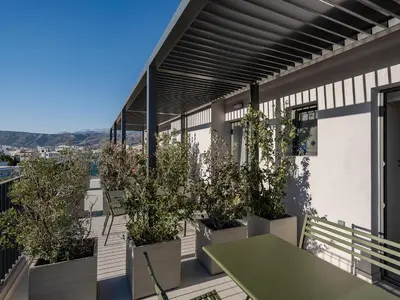 a balcony with potted trees and a green table at Arkadi Hotel in Chania Town