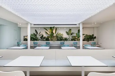 a waiting room with tables and chairs and plants at Arkadi Hotel in Chania Town