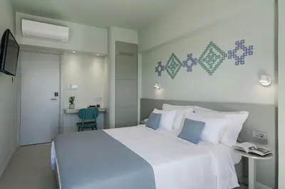 a bedroom with a large white bed with blue accents at Arkadi Hotel in Chania Town