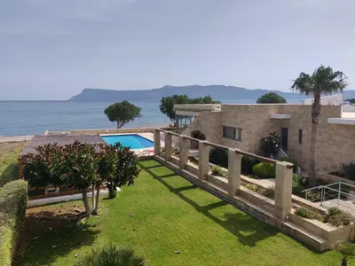 a villa with a swimming pool next to the ocean at Viglia Beach Apartments in Kissamos