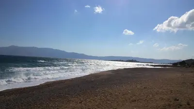 a beach with the ocean and mountains in the background at Viglia Beach Apartments in Kissamos