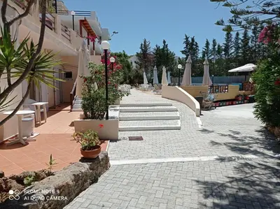 a walkway leading to a resort with tables and chairs at Alexandros Studios in Kalamaki Chanion