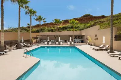 a pool with chaise lounge chairs and palm trees at Sea View Hotel & Apartments in Kato Daratso