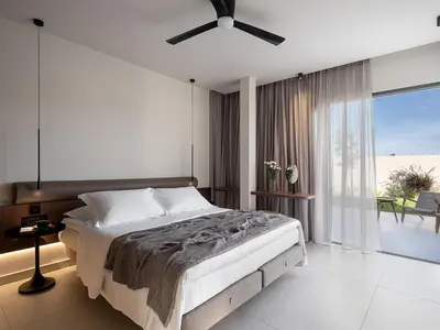 a bedroom with a bed and a ceiling fan at Pnoe Villas - Seafront Experience in Tavronitis