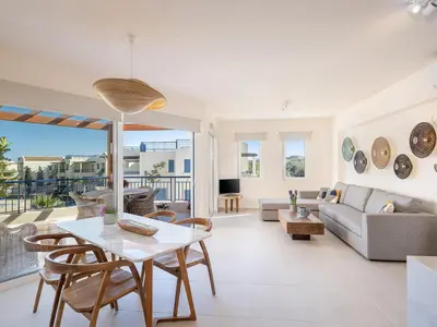 a living room with a table and chairs and a couch at Calmaliving Seaside apartments with pool in Gerani Chanion