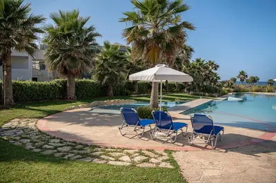 two chairs and an umbrella next to a swimming pool at Calmaliving Seaside apartments with pool in Gerani Chanion
