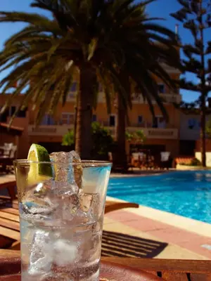 a glass of water with a lime on a table next to a pool at Kissamos Hotel in Kissamos