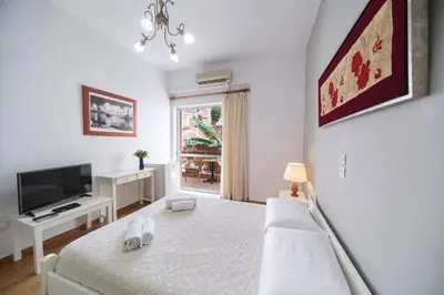 a white bedroom with a bed and a television at Casa Kasteli in Chania Town