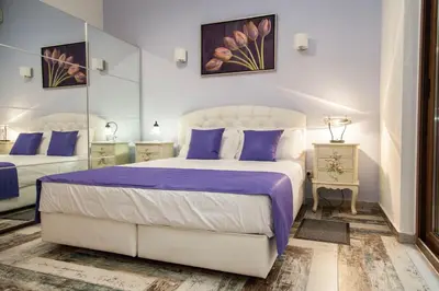 a bedroom with a white bed with purple sheets and mirrors at Casa Kasteli in Chania Town