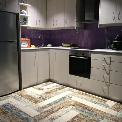 a kitchen with white cabinets and a wooden floor at Casa Kasteli in Chania Town