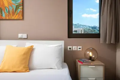 a bedroom with a bed with a yellow pillow and a mirror at Halepa Luxury Apartments in Chania Town