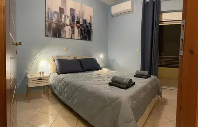 a bedroom with a large bed with a night stand and a window at Centro Apartment in Chania Town