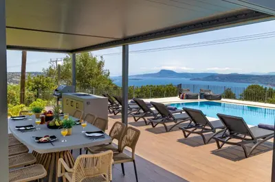 a patio with a table and chairs and a pool at SeaSilia Luxury Villa in Korakiaí