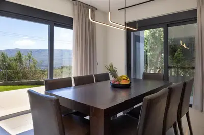 a dining room with a table and chairs and a large window at SeaSilia Luxury Villa in Korakiaí