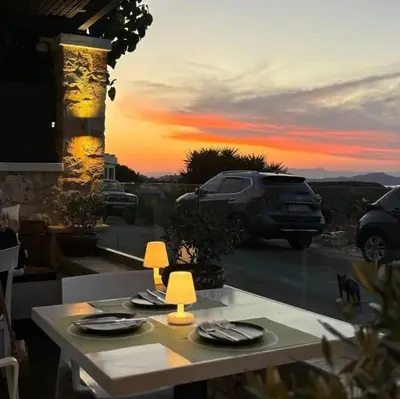 a table with plates and chargers on it with a sunset at Alexis Hotel in Chania Town