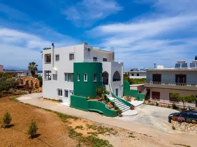 a large white building with green doors and a yard at Thelma and Louise house in Mourniaí