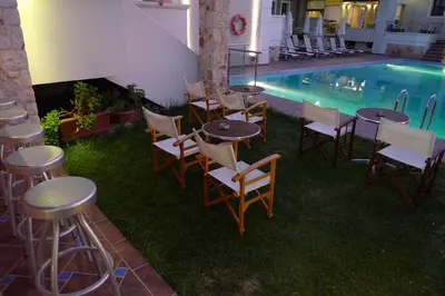 a group of tables and chairs next to a swimming pool at Theros Hotel in Tavronitis