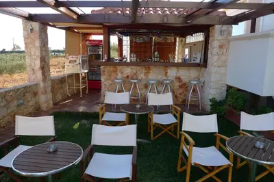 a patio with tables and chairs and a bar at Theros Hotel in Tavronitis