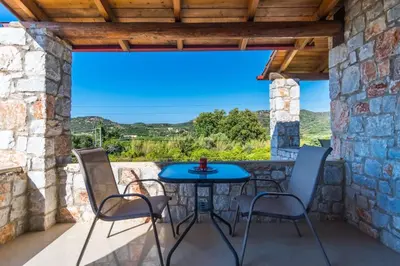 a patio with a blue table and chairs on a stone wall at Villa Vicina - In Platanias and 4min by the beach in Chania Town