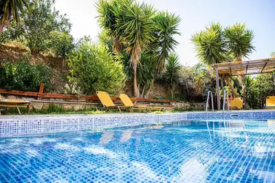 a swimming pool with yellow chairs and palm trees at Villa Vicina - In Platanias and 4min by the beach in Chania Town