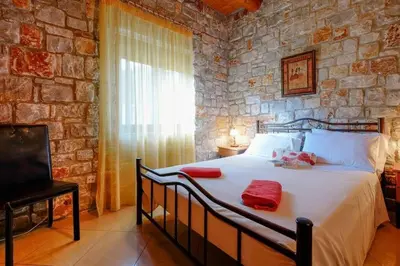 a bedroom with a large bed in a stone wall at Villa Vicina - In Platanias and 4min by the beach in Chania Town