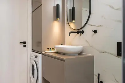 a bathroom with a sink and a washing machine at Orama Luxury Apartments in Agia Marina Nea Kydonias