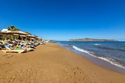 a beach with chairs and umbrellas and the ocean at Beachfront villa Agia Marina in Stalos