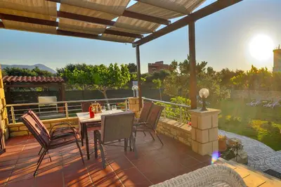 a patio with a table and chairs on a deck at Villa Archontissa in Análipsis