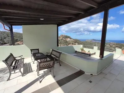 a patio with two chairs and a table on a roof at Villa Chloe - Amazing view Villa with swimming pool in Chania Town