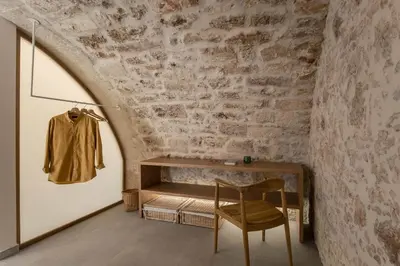 a room with a table and a chair next to a brick wall at Lindas Convent Garden Home 1 in Chania Town