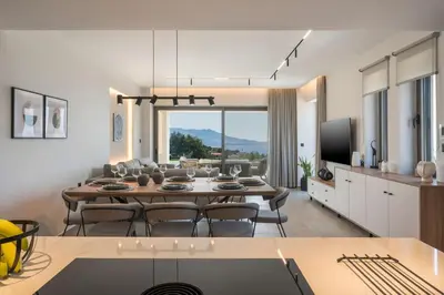 a kitchen and living room with a table and chairs at Villa Ekphrasis with sea view and jacuzzi in Ravdhoúkha
