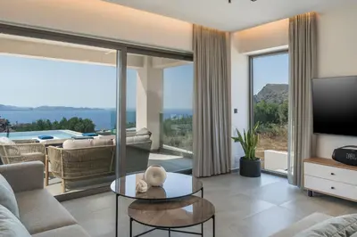 a living room with a couch and a tv at Villa Ekphrasis with sea view and jacuzzi in Ravdhoúkha