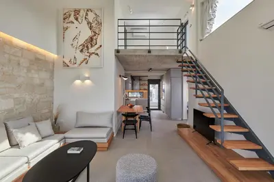 a living room with a staircase and a couch and a table at Pachnes Luxury Apartments - Heated Pool, Sea View in Kounoupidhianá