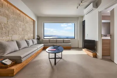 a living room with a couch and a large window at Pachnes Luxury Apartments - Heated Pool, Sea View in Kounoupidhianá