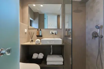 a bathroom with a sink and a mirror and a shower at Pachnes Luxury Apartments - Heated Pool, Sea View in Kounoupidhianá