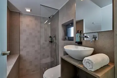 a bathroom with a sink and a toilet and a shower at Pachnes Luxury Apartments - Heated Pool, Sea View in Kounoupidhianá
