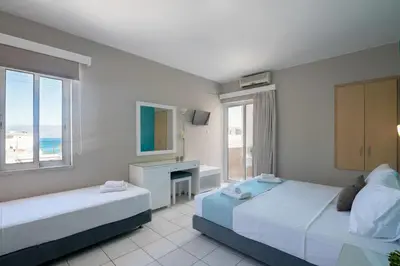 a bedroom with two beds and a desk and window at Hermes Hotel in Kissamos