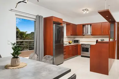 a kitchen with wooden cabinets and a large window at The Cozy Nook in Chorafakia